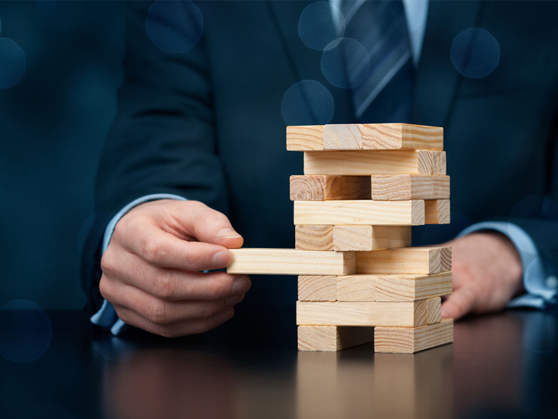 Businessman remove one piece from jenga tower Risk management concept metaphor