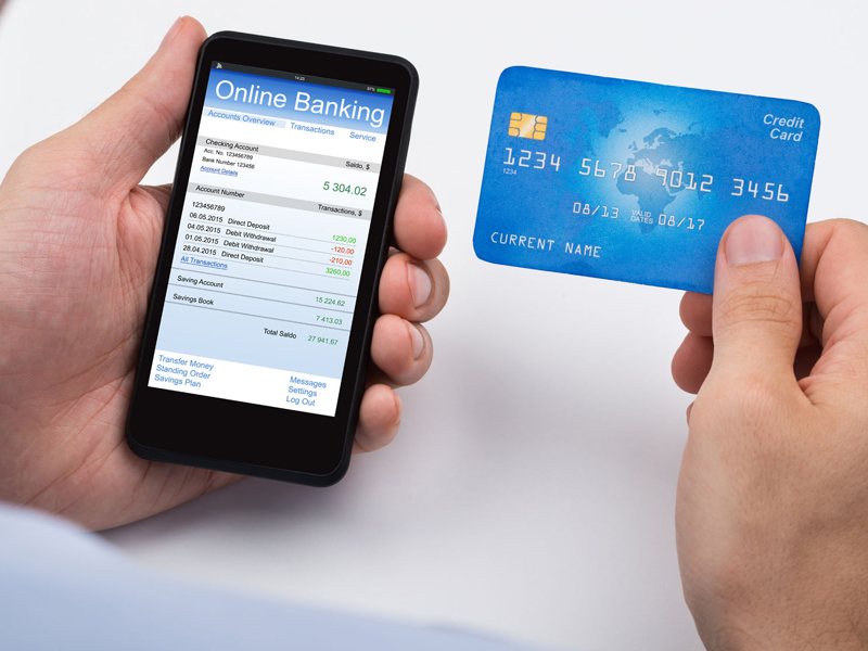 Close-up Of Person With Credit Card And Mobile Phone Doing Online Banking