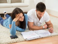 Worried Young Couple Lying On Carpet Calculating Their savings, planning future, retirement fund