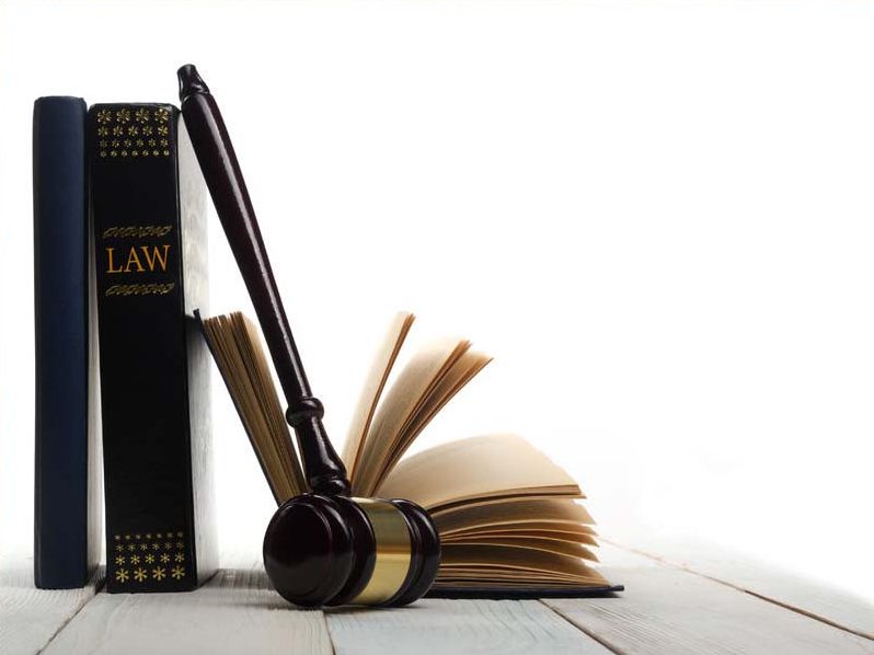 Open law book with a wooden judges gavel on table in a courtroom or law enforcement office isolated on white background