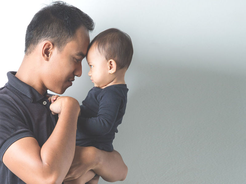 a portrait of a young asian father holding his adorable baby on white background