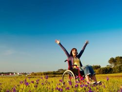 Young woman on a wheelchair over a green meadow
