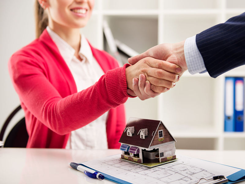 female homebuyer shakes hand with real estate agent in office