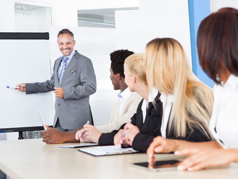 businesspeople looking at businessman explaining in presentation