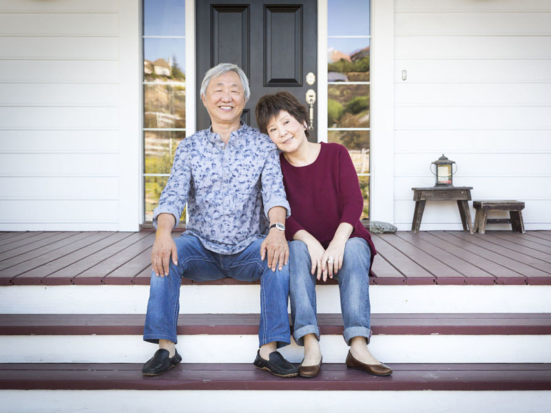 tractive happy senior chinese couple sitting on the front steps of their house.