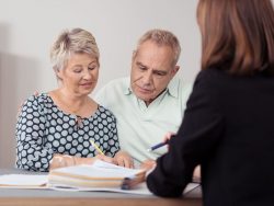 middle aged couple discussing something on a document with a female advisor at the table