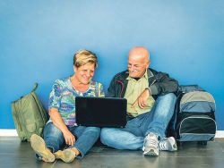 Mature couple travelling with backpacks and laptop