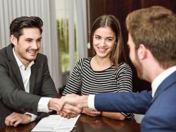 smiling young couple shaking hands with investment advisor