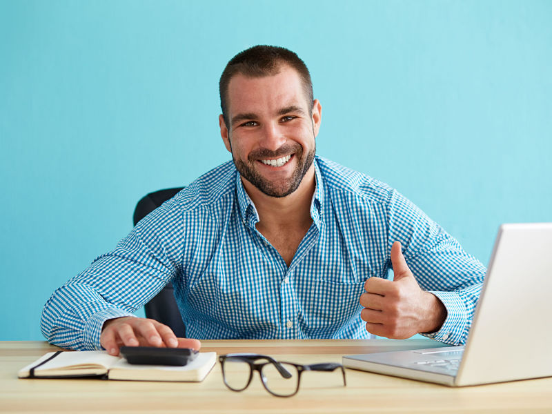 Smiling businessman calculates taxes and gesturing thumbs up
