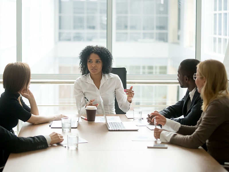 Black female boss leading corporate multiracial team meeting talking to diverse businesspeople, african american woman executive discussing project plan at group multi-ethnic briefing in boardroom
