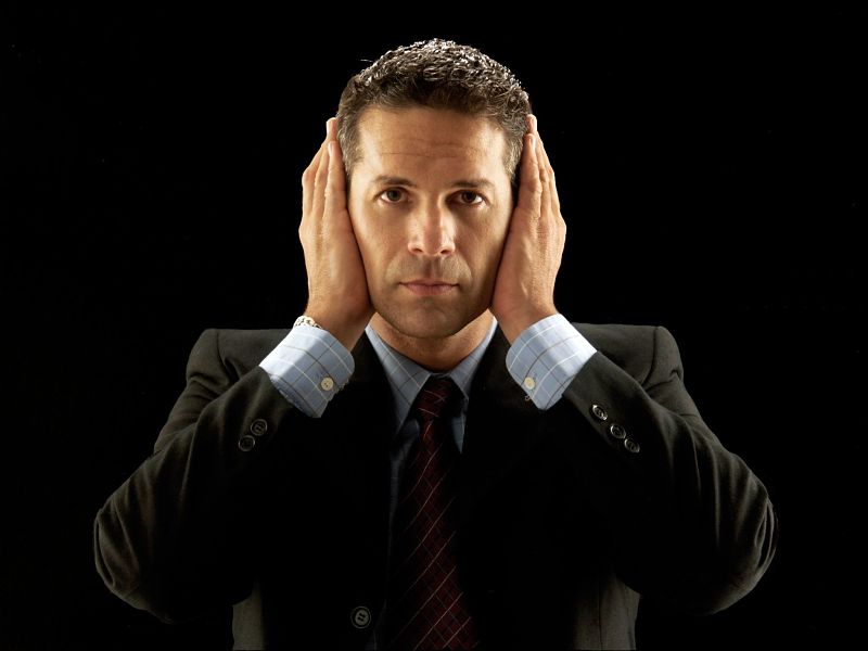 businessman covering his ears on black background