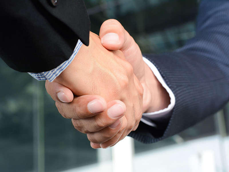 Close up of businessman hands making handshake - greeting, dealing, merger and acquisition concepts