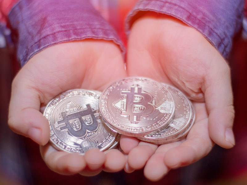 Bitcoin in the hands of a child. The boy holds a metal coin of crypto currency in his hands.