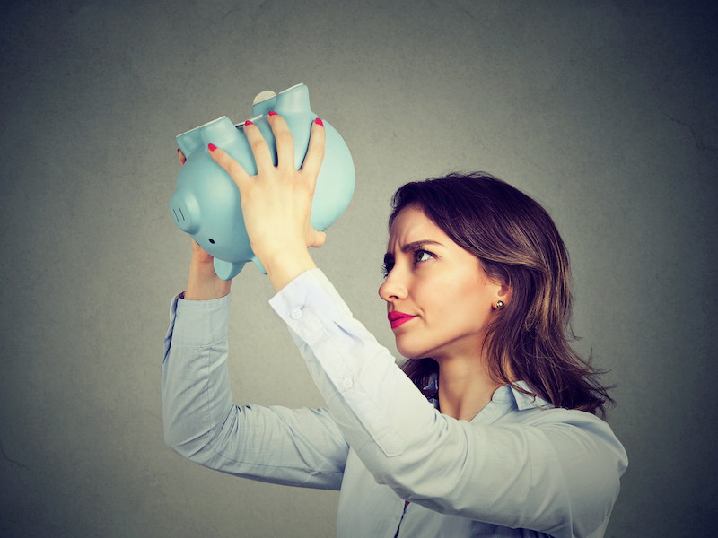 Young worried woman with empty piggy bank