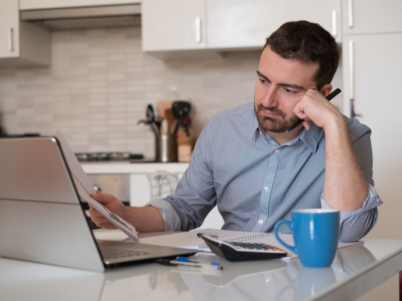 Frustrated man calculating bills and tax expenses