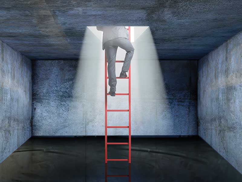 man climbing ladder out of darkness