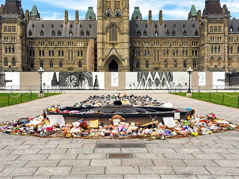 Ottawa, Canada - June 30, 2021: The many shoes and toys left near the Centennial Flame on Parliament Hill in memory of the children whose remains were found near former Residential Schools.