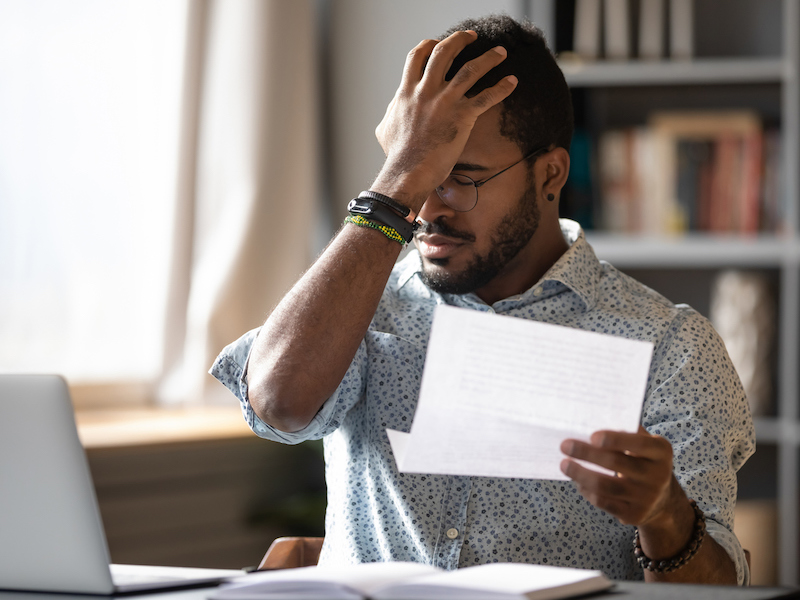 African businessman holding letter reading bad bank news about debt