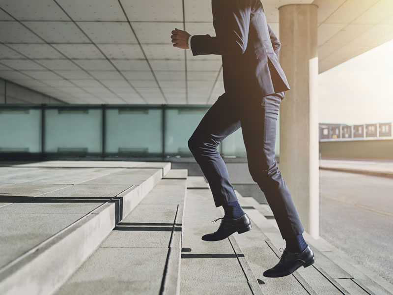 A man in a suit walking up concrete steps.