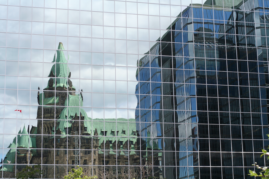 Canadian parliament buildings reflected in glass office building
