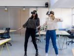 Two businesswoman using virtual reality glasses at new office to enter the metaverse stock photo