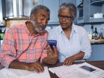 Couple looking at calculator and paper documents in their kitchen