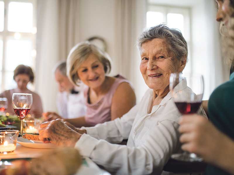 Senior woman smiling surrounded by people at a dinner party