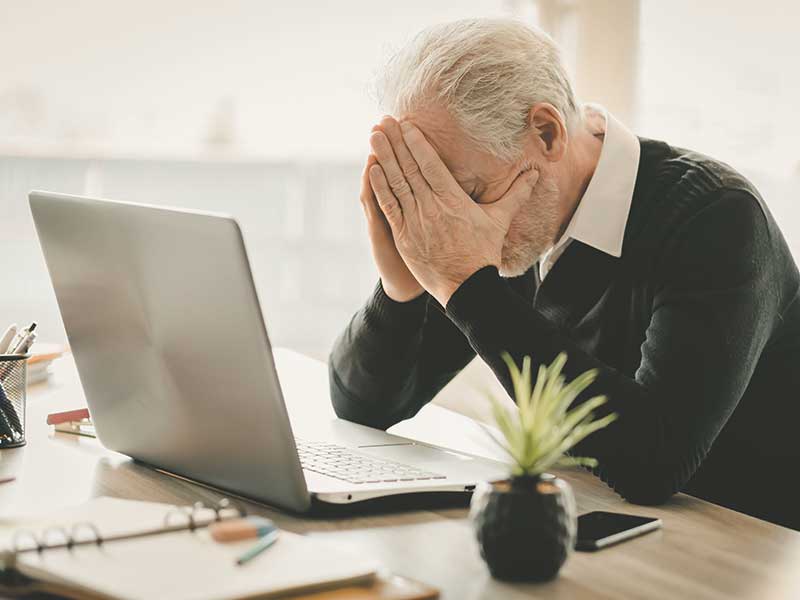 Man sitting in front of computer holding his face in frustration