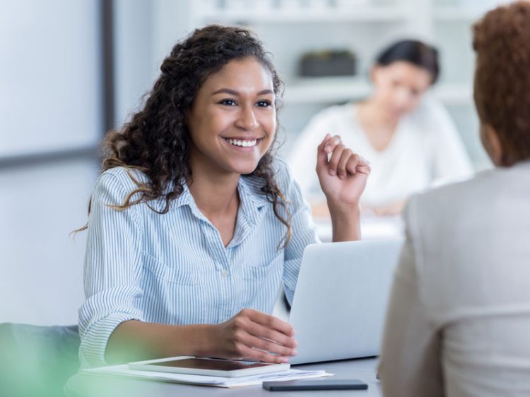 Businesswoman smiles while listening to colleague