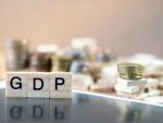 GDP Word Written In Wooden Cube reflection on black mirrow with money stack as graph in background stock photo
