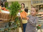 Boy in supermarket with bunch of carrots