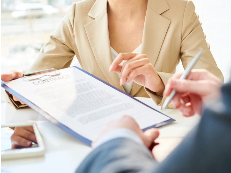 Young businesswoman with smile holding contract showing it to client