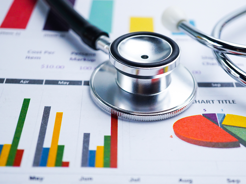 A stethoscope laid on paper featuring charts and graphs.