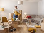 Smiling young woman surrounded by boxes while moving unpacking personal belongings