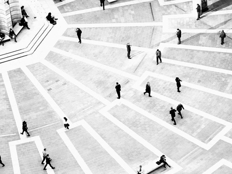 Bird’s eye view of several businesspeople walking on pavement, image in black and white